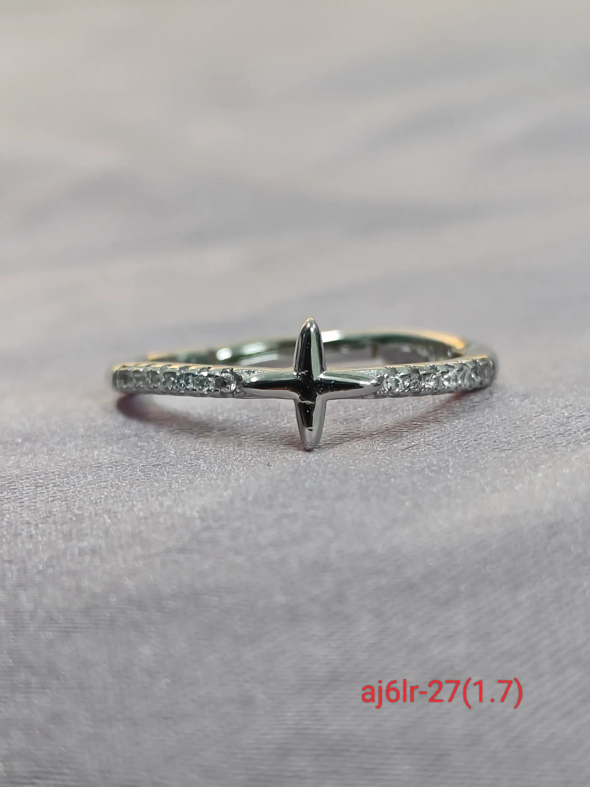 Silver ring with a cross design on a gray background